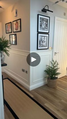 a living room filled with furniture and pictures on the wall next to a doorway that leads to a hallway