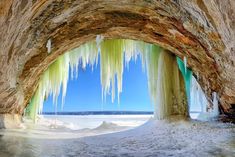 an ice cave with icicles hanging from it's ceiling and water in the background