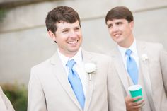 two men in suits and one is holding a cup