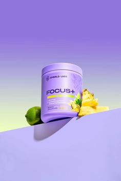 a can of focus plus next to a pile of bananas and limes on a purple background