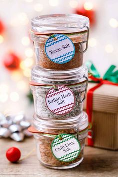 three glass containers filled with spices next to a christmas tree