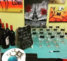 there are many wine glasses on the table with signs and bottles in front of them