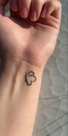 a woman's wrist with a small heart tattoo on the left side of her arm