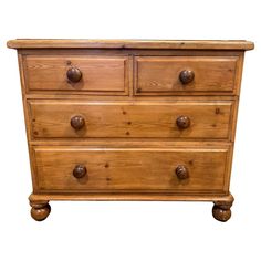 a wooden dresser with three drawers and two knobs on the top drawer, against a white background