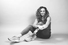 a black and white photo of a woman sitting on the ground with her legs crossed