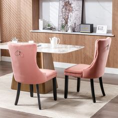 two pink chairs sitting next to each other at a table