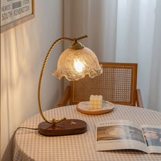 a lamp on top of a table next to an open magazine and plate with food