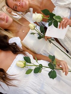 two beautiful young women in white dresses holding roses