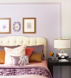 a bedroom with purple walls and pictures on the wall above the bed, along with two nightstands