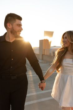 a man and woman hold hands as the sun shines down on them behind them