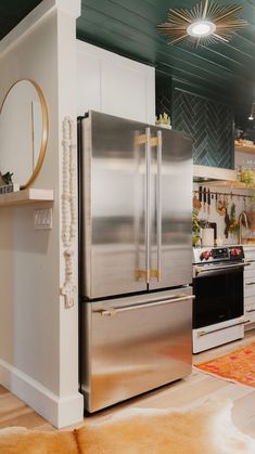 a stainless steel refrigerator and stove in a kitchen with green ceiling tiles on the walls