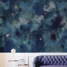 a couch sitting in front of a wall covered in stars and space paint on it