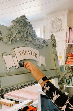 a woman is painting the side of a green bed with white paint and writing on it