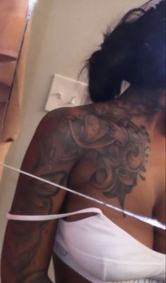 a woman with tattoos on her back is holding a string in front of her body