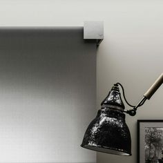 a black and white photo of a lamp on a desk next to a framed photograph