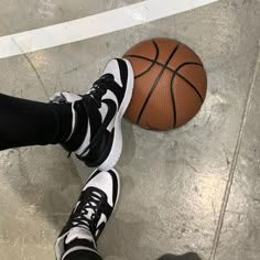 a person standing next to a basketball on top of a cement floor with their feet in the air