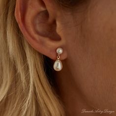 a woman wearing a pair of earrings with pearls on the side of her ear,