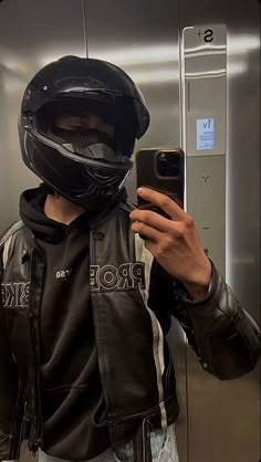 a man wearing a motorcycle helmet taking a selfie with his cell phone in front of him