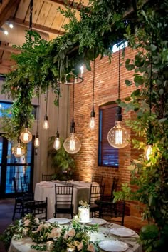 an indoor dining area with hanging lights and greenery