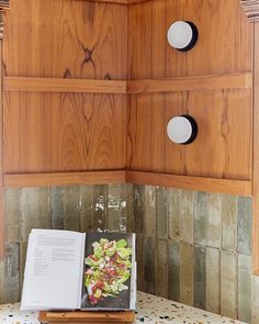 an open book sitting on top of a kitchen counter next to a wooden cabinet with knobs