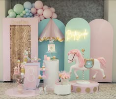 a pink and blue birthday party with a carousel, cake stand, cupcakes and balloons