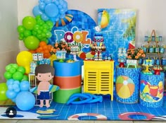 a birthday party with balloons, decorations and paper goods on the counter top in front of a blue tiled wall