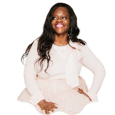 a woman sitting on the ground with her hands on her hips and smiling at the camera