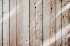 the wooden wall is made of planks and has been painted white with some light shining on it