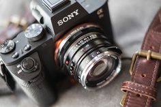 a camera sitting on top of a table next to a brown leather case and strap