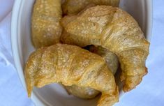 three croissants in a white bowl on a table