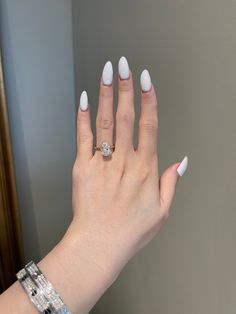 a woman's hand with white manicured nails and a diamond ring