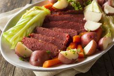 a white plate topped with meat and veggies on top of a wooden table