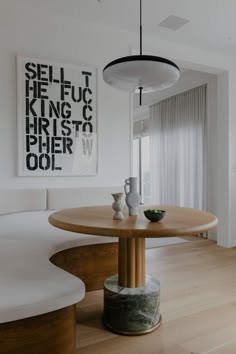 a dining room table with two vases on it and artwork hanging above the table