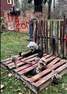 two skeletons are sitting on top of a pallet in front of a wooden fence