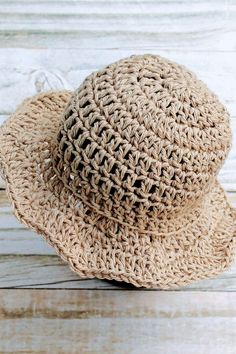 a close up of a straw hat on a wooden surface with white boards in the background