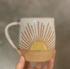 a hand holding a coffee cup with sun design on it