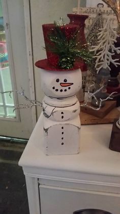 a snowman is sitting on top of a white cabinet next to a christmas tree