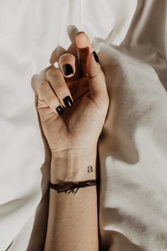 a woman's arm with a black and white tattoo on it, resting on a bed