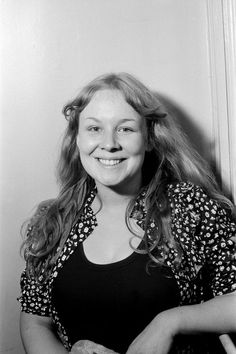 a black and white photo of a woman with her hands on her hips, smiling