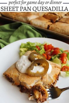 a white plate topped with a piece of pie next to a salad and a fork