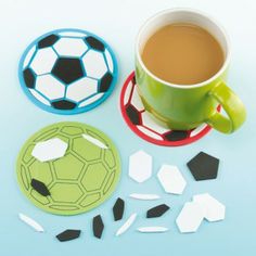 a cup of coffee sitting next to two plates with soccer balls on them