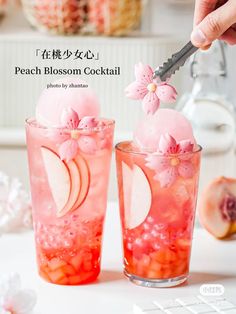 two glasses filled with peach blossom cocktail on top of a table