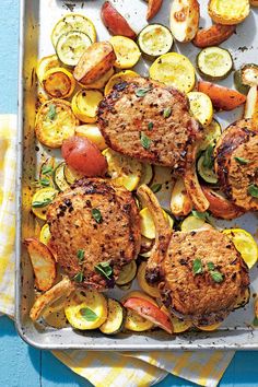 a tray filled with meat and vegetables on top of a blue table next to a yellow towel