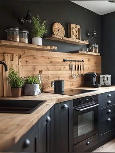 a kitchen with black cabinets and wooden shelves on the wall, along with potted plants