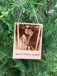 an ornament hanging from a christmas tree with a couple in the photo on it