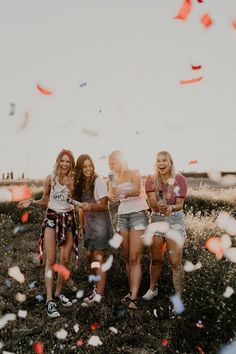 three girls are standing in a field with confetti