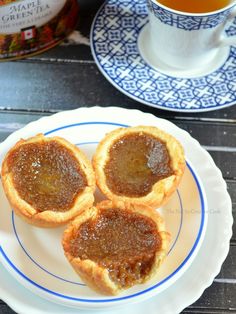 three small pastries on a plate next to a cup of tea