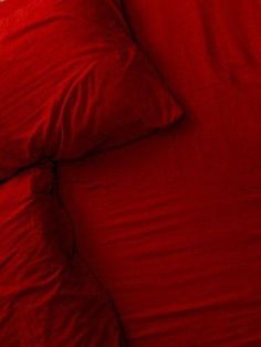 a bed with red sheets and pillows on it