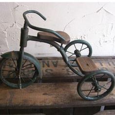 an old tricycle sitting on top of a wooden bench