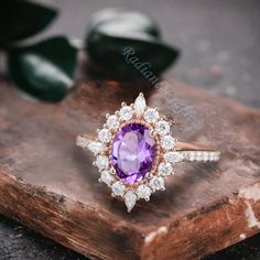 an oval shaped amethorate and diamond ring sitting on top of a wooden slab